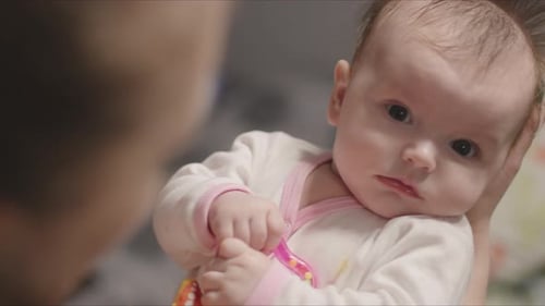 Cute Baby with Fuzzy Hair Being Held Indoors