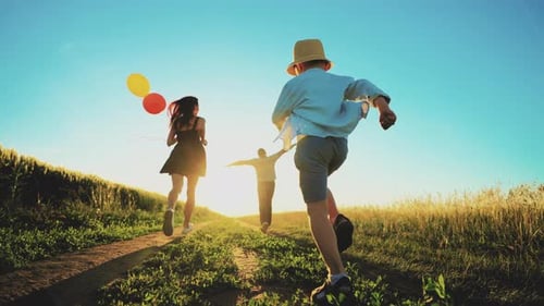 View From Back of Happy Family Dad Momchild Running Across Field Walk Outdoors in Sunny Summer with