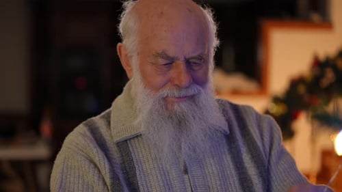 Senior Man Decorates Christmas Tree with Lights