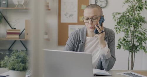 Ambitious Business Lady Discussing Work on Mobile Phone and Using Laptop in Office