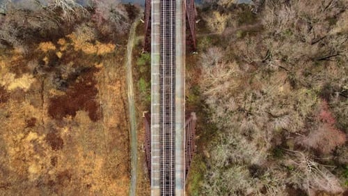 Drohnenvideo aus der Luft, von oben nach unten, eines Eisenbahnbrückenviadukts, das über ein Tal und einen Bach in t führt