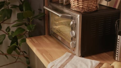 Woman Baking in Kitchen Puts Tray in Oven