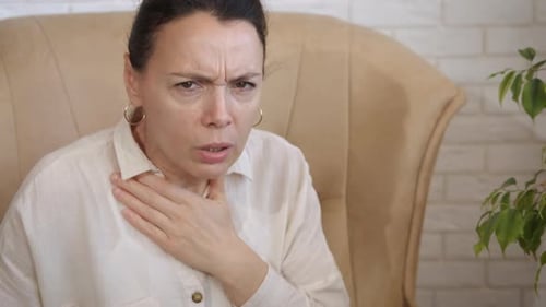 Woman Coughing and Clutching Throat in Living Room