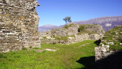Ruined stone walls of medieval castle with mountain background on a sunny day