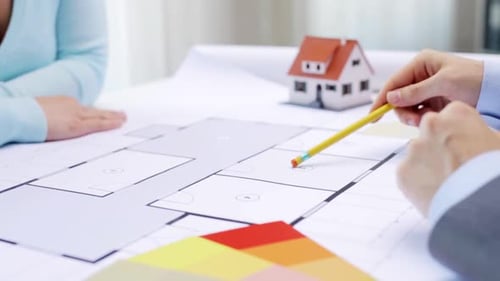 Architects Reviewing Blueprints with Model House and Colors