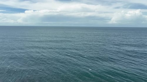 Aerial view of dark sea with waves and cloudy sky during day time.