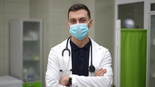 Nahaufnahme in Zeitlupe Ein männlicher Arzt in einem weißen medizinischen Kittel steht verschränkt auf seinen Armen in der