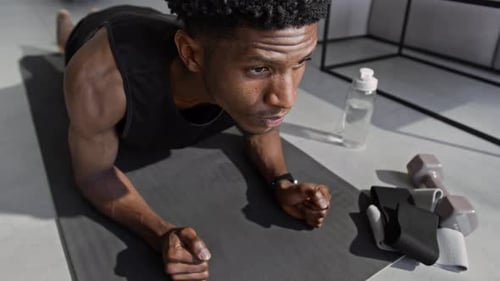 Athletic Man Doing Plank Exercise on Mat Indoors