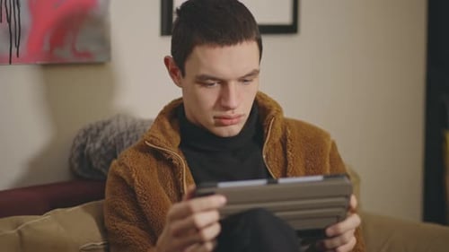 Young Man Using Tablet Device on Sofa