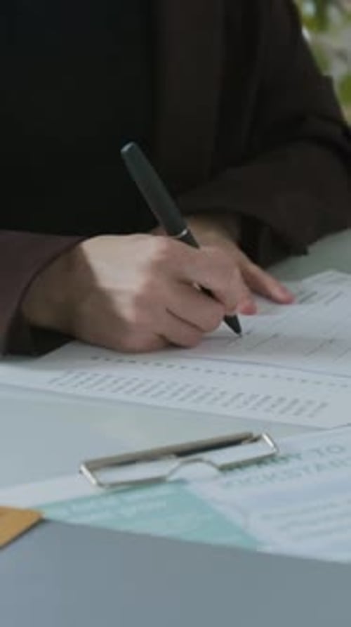 Woman Signing Business Loan Agreement and Handing It to Bank Officer