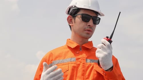 Männlicher Ingenieur in Arbeitsschutzkleidung spricht mit einem Kollegen auf einem Walkie-Talkie.
