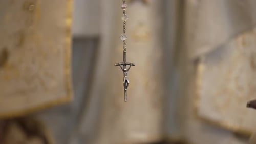Silver Crucifix and Rosary Beads Hanging Vertically