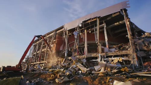Excavator Dismantles Destroyed Hockey Stadium in Evening