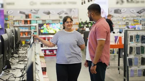 Indian Couple Choosing New Plasma Tv in Home Appliance Store
