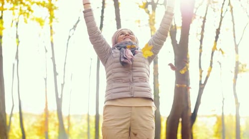 Woman Enjoys Throwing Leaves in Autumn Forest