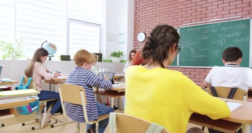 Caucasian Teens Kids Sitting at Desks and Using Gadgets Teacher with Pupils in Classroom School