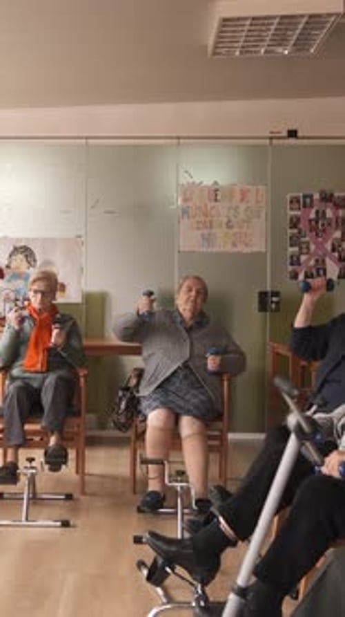 Senior Men and Women Doing Pedal Exercises and Lifting Dumbbells at Rehabilitation Center