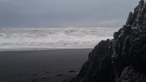 Black Sand Beach, Iceland. Rough Sea Waves Crashing in Front of Black Basalt Rock on Cold Rainy Day