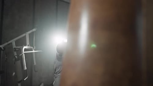 Boxer Training Hitting Punching Bag African American Sweated Sportsman Practicing Punches in Gym