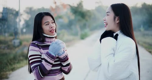Two Asian women standing and talking happily in the morning.
