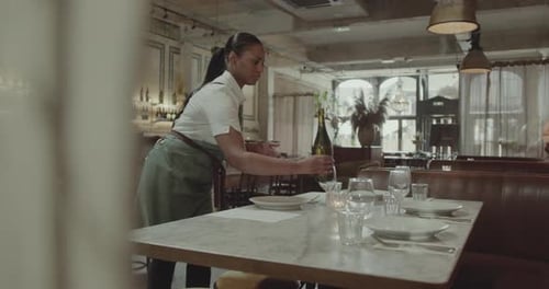 Camarera preparándose para el servicio, poniendo la mesa en un restaurante
