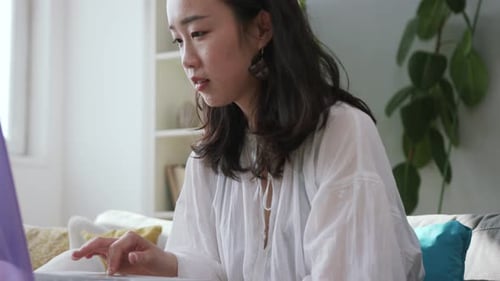 Young Woman Uses Laptop on Couch Indoors