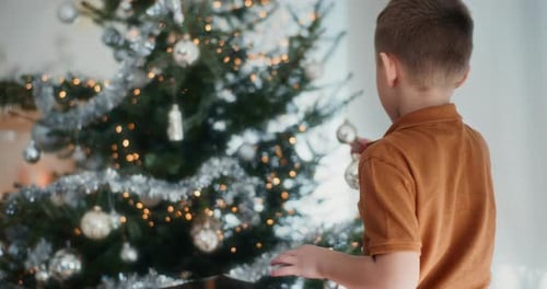 Boy Decorating Christmas Tree with Silver Ornaments