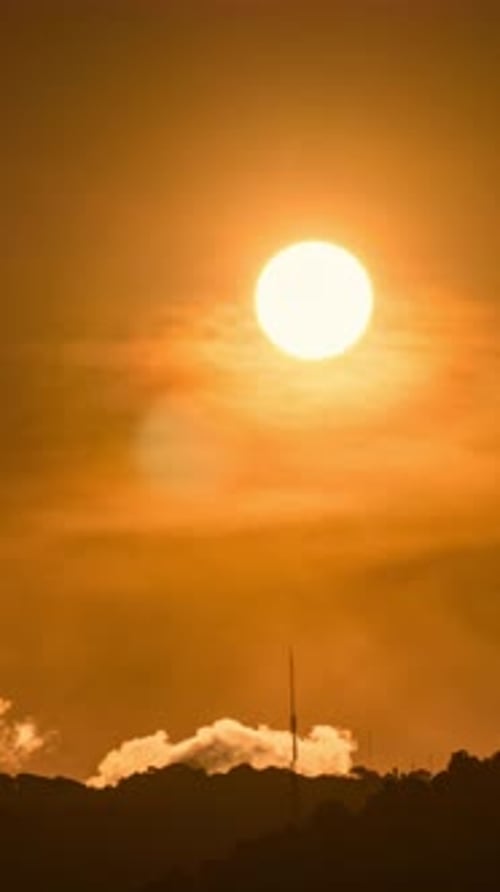 Timelapse of dramatic sunrise with orange sky in a cloudy day.