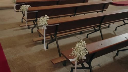 church pews decorated with white flowers and ribbons for wedding