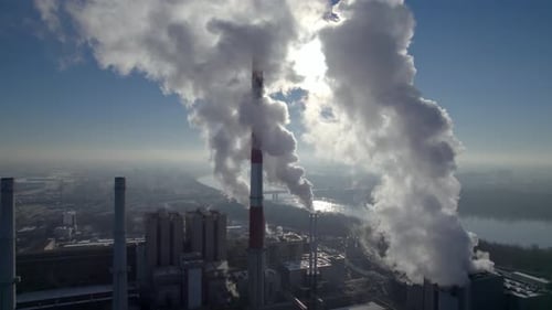 Aerial dolly shot of a coal-fired heating power plant with thick white smoke coming from the chimney
