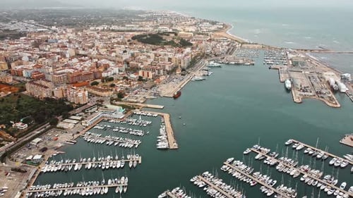 Port town from drone aerial shot. Reveal of blue water with waves, large docks with boats.