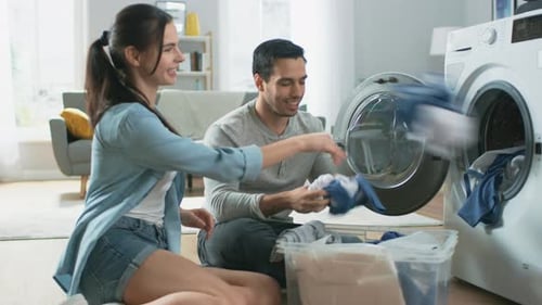 Cheerful Couple Doing Laundry Together in Living Room