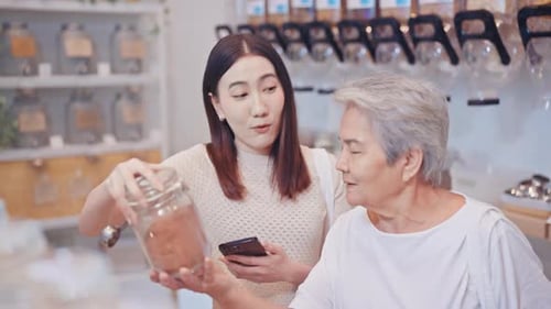 Young woman and senior woman smiling while shopping in a refill store