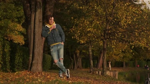 Young Adult Relaxing in Autumn Park with Drink