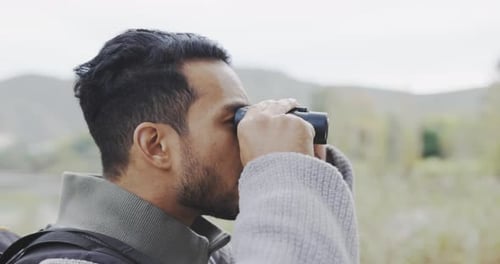 Nature, hiking and man with binoculars, adventure holiday in countryside and happy view in field
