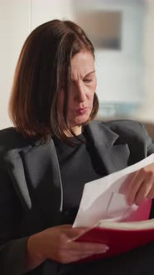 Businesswoman Examining Documents Indoors in Professional Office Setting