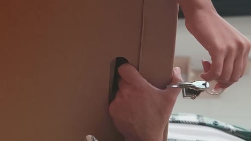 Hands Opening Cardboard Box with Keys Indoors