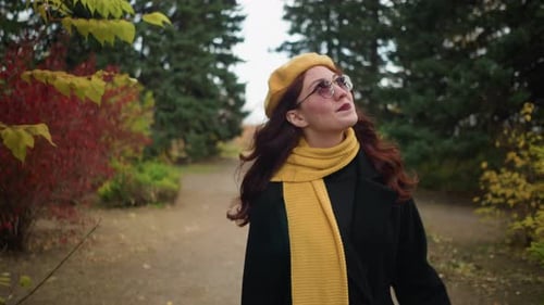 RedHaired Artist Adjusts Hair in Autumn Garden with Yellow Beret