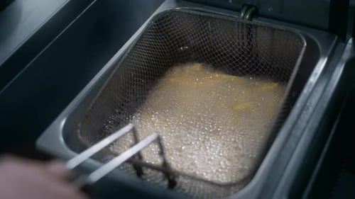 person frying French fries in a snack bar