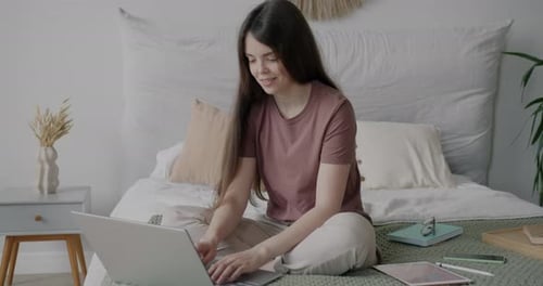 Young Woman Using Laptop Computer in Bed at Home