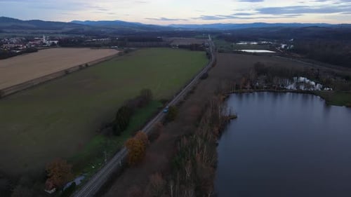 Vista aérea dos trilhos de trem no meio da natureza cercada por campos e trens.