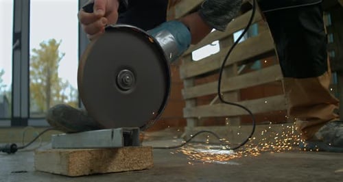 Worker Cuts Metal with Grinder Indoors, Sparks Flying
