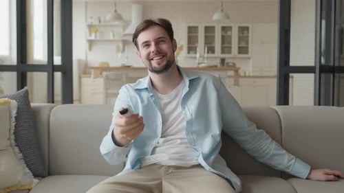 Smiling Man Relaxing on Couch with Remote Control