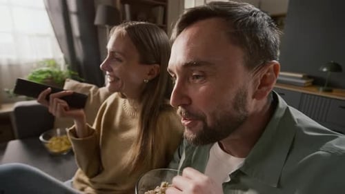 Husband and Wife Laughing Aloud at Gags while Watching Sitcom on TV