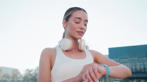 Young Female Runner Looks at Smartwatch Device Fitness Bracelet Heart Rate Pulse SPO2 in City Park