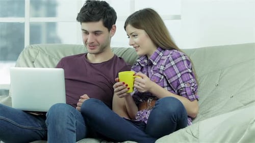 Couple Relaxing on Couch with Laptop and Coffee