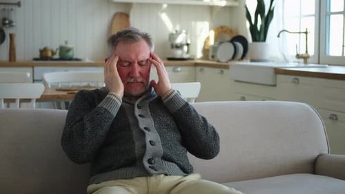 Senior Man Rubbing Temples Experiencing Headache