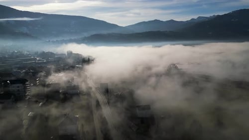 A Drone Flies Over a Mountain Village Covered in Morning Fog