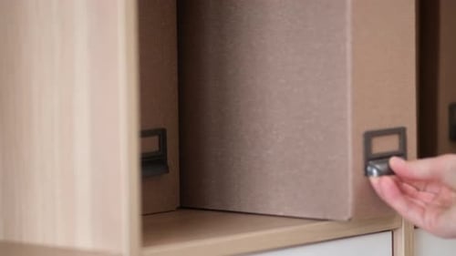 A woman hand takes out a documents folder from the closet, close-up