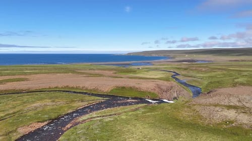 Aerial view of a winding river flowing toward the Greenland Sea in Austurland, Iceland, capturing